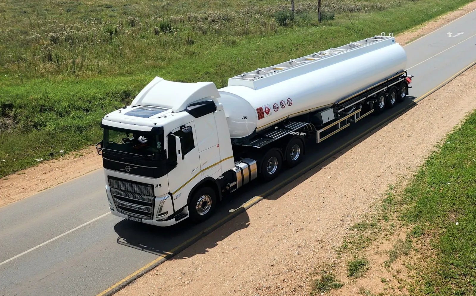White tanker truck driving on a rural road